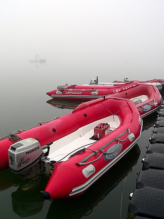 Red inflatable rescue boats docked in foggy harbor