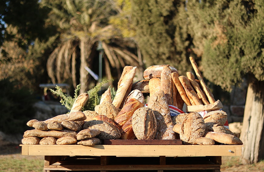 Assortment of fresh artisan bread on wooden table outdoors