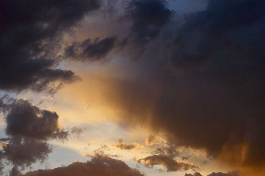Dramatic sunset sky with golden light breaking through dark clouds