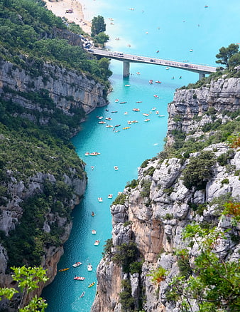 Aerial view of turquoise river gorge with boats and bridge