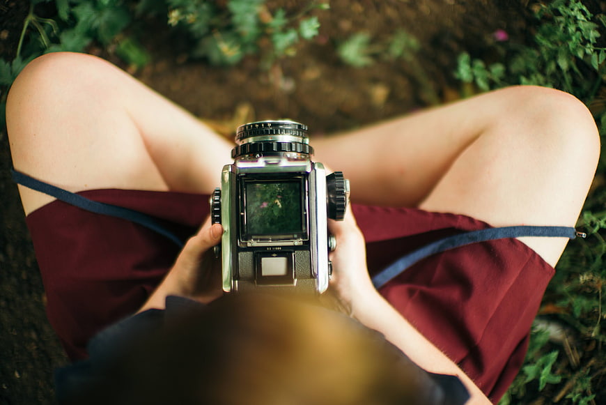 Woman holding vintage medium format film camera outdoors