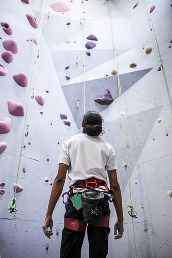 Rock Climber Facing Indoor Wall with Chalk and Harness