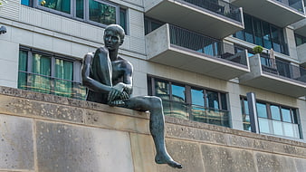 Bronze statue of sitting man on stone wall in Berlin