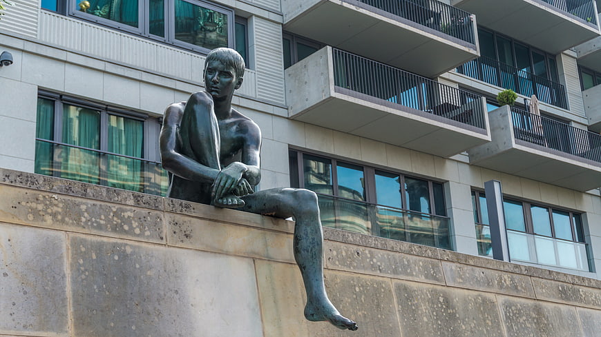 Bronze statue of sitting man on stone wall in Berlin