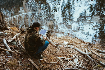 Man operating drone controller in snowy mountain forest