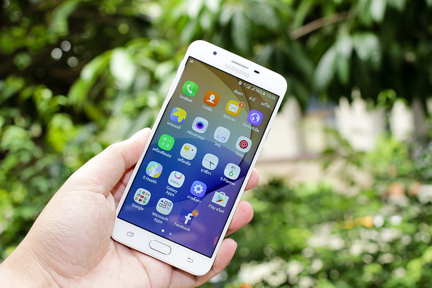 Hand holding white Samsung smartphone with app icons