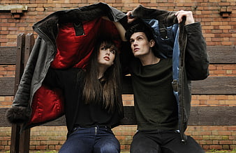 Couple Sheltering Under Jackets on Park Bench