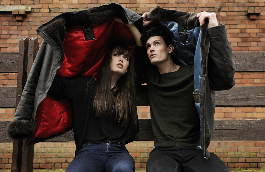 Couple Sheltering Under Jackets on Park Bench