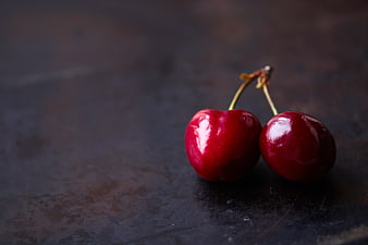 Two Fresh Red Cherries on Dark Textured Background