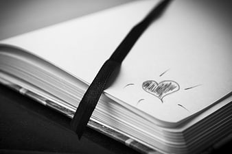 Open notebook with pencil heart doodle and black ribbon bookmark