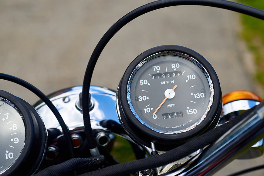 Close-up of vintage motorcycle speedometer and chrome handlebars