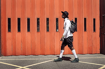 Stylish man walking past vibrant orange wall