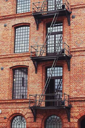 Red brick building facade with black metal fire escape stairs