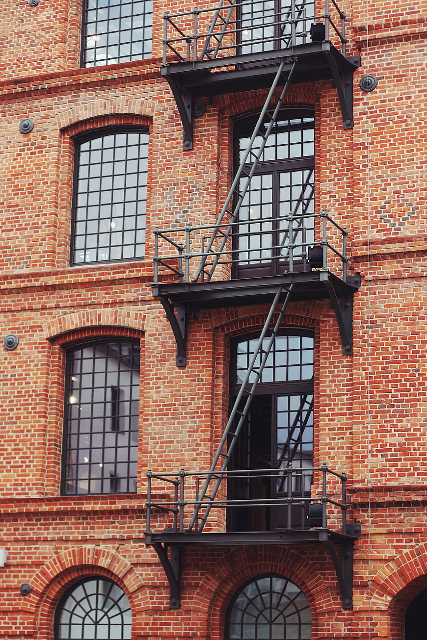 Red brick building facade with black metal fire escape stairs