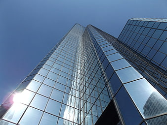 Low angle view of modern glass skyscraper against blue sky