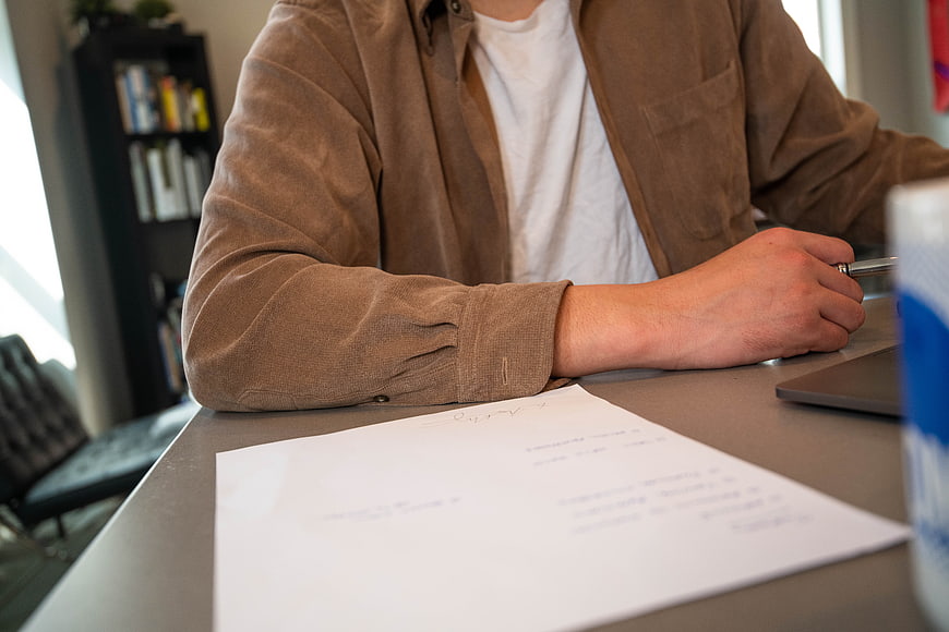 Man Signing Documents at Desk with Pen