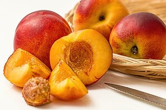 Fresh ripe peaches with slices and pit on white background