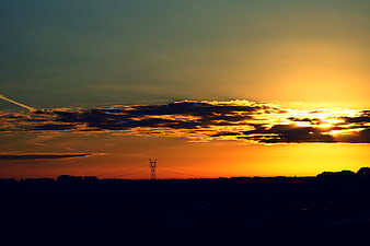 Dramatic sunset over silhouette landscape with power lines