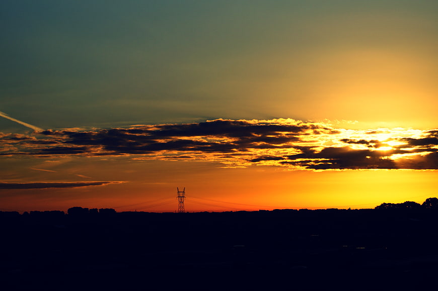 Dramatic sunset over silhouette landscape with power lines