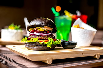 Gourmet black burger with jalapenos and fries on wooden board