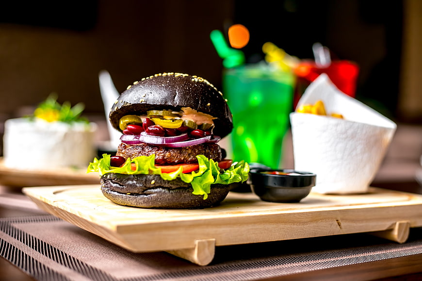 Gourmet black burger with jalapenos and fries on wooden board
