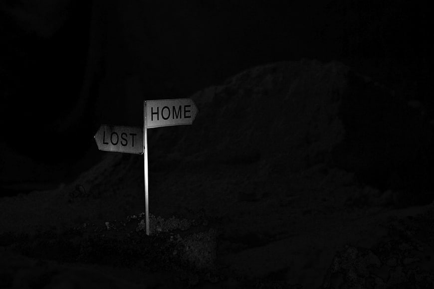 Dark signpost pointing to home and lost at night