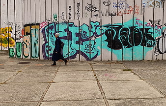 Woman walking past colorful graffiti wall in urban setting