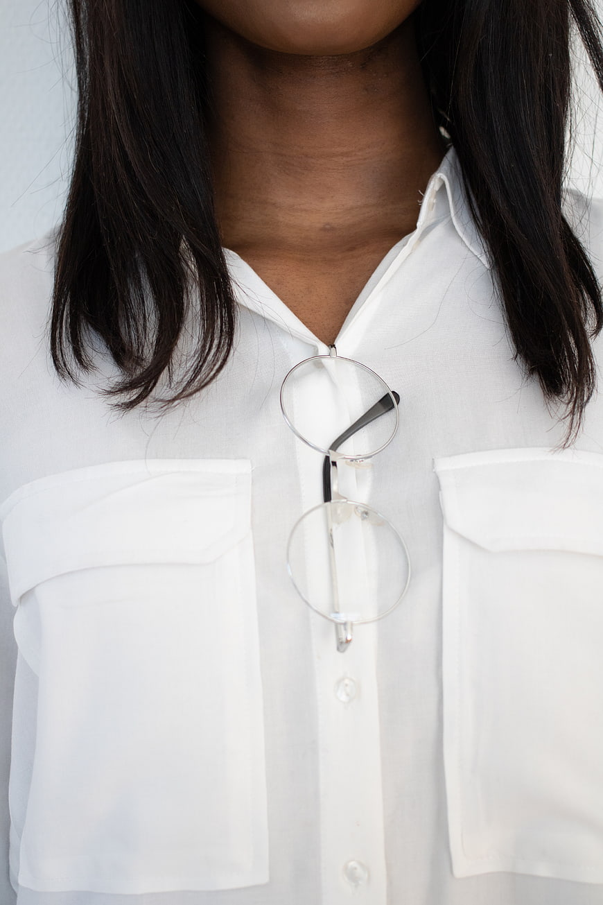 Close-up of woman wearing white shirt with glasses tucked in collar