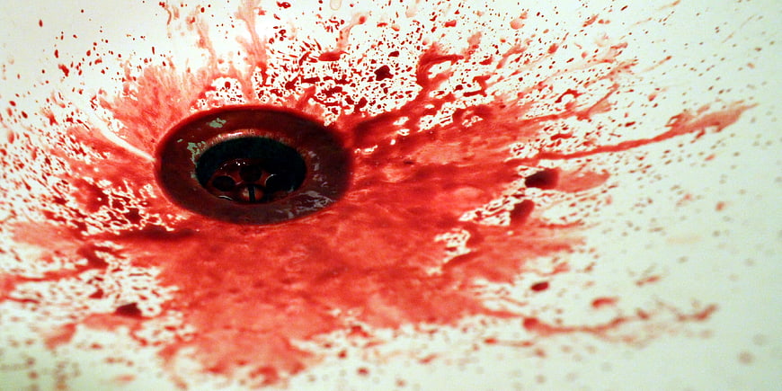 Red liquid splatter in white sink drain