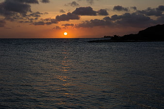 Serene Sunset Over Ocean with Silhouette Coastline