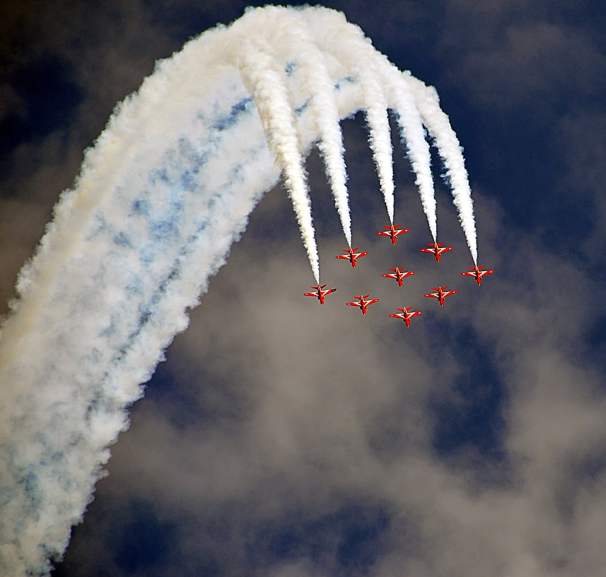 Red aerobatic jets in formation with smoke trails