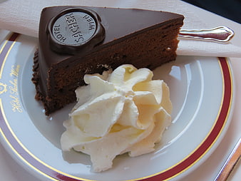 Classic Sacher Torte Slice with Whipped Cream on Hotel Plate