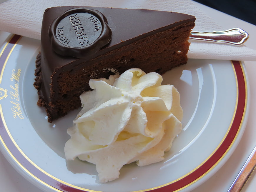 Classic Sacher Torte Slice with Whipped Cream on Hotel Plate