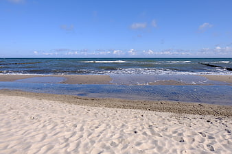 Sandy beach with gentle waves and blue sky