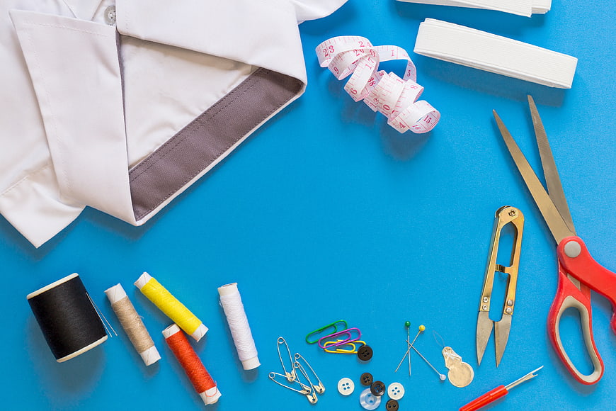 Sewing tools and white shirt on blue background