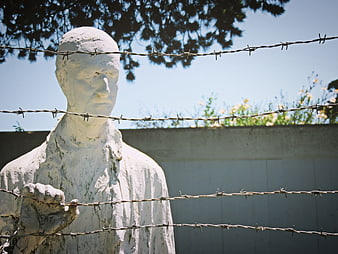 White Statue Behind Barbed Wire Fence Memorial