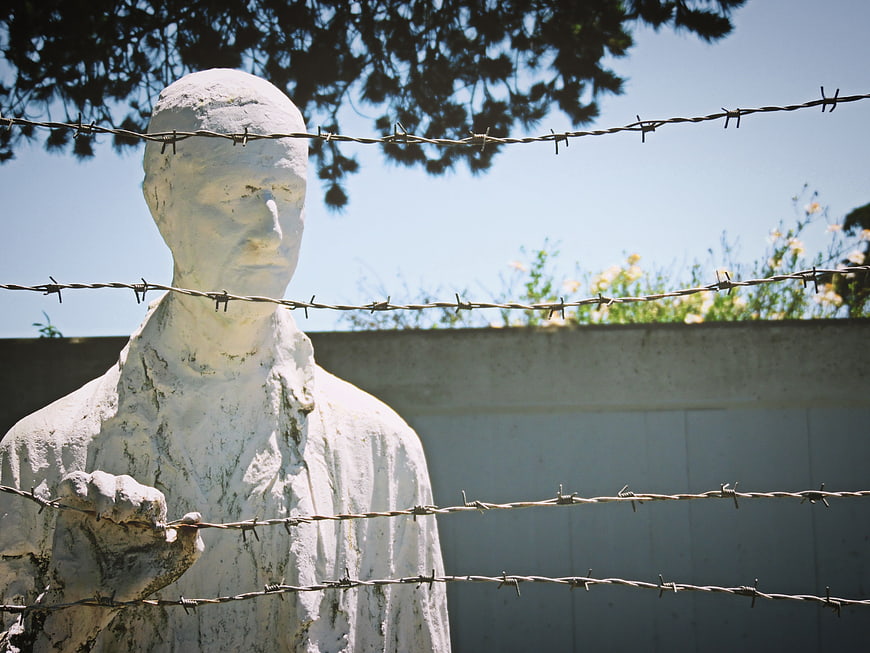 White Statue Behind Barbed Wire Fence Memorial