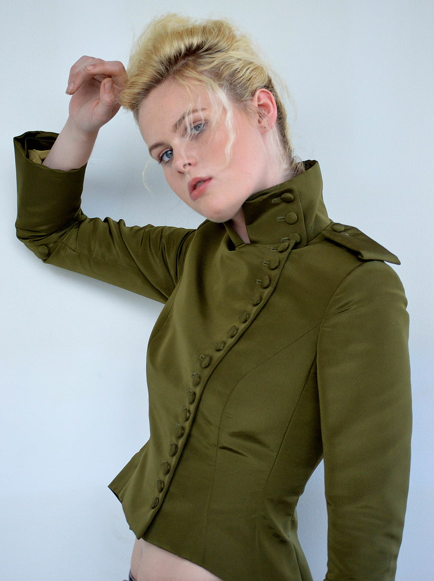 Blonde woman in olive green military jacket posing