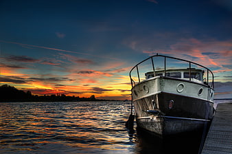 Vintage Boat Docked at Sunset with Vibrant Sky