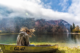 Man with Dreads Sitting in Yellow Boat by Lake