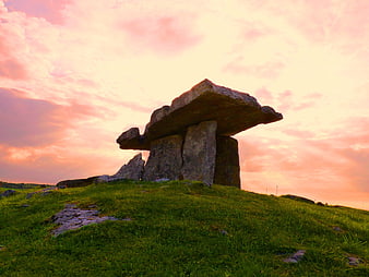 Ancient Dolmen Stone Structure on Green Hill at Sunset