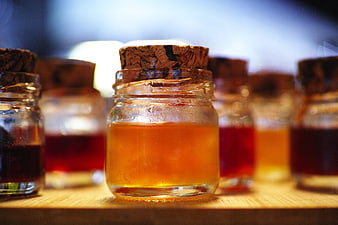 Glass Jars of Honey and Jam with Cork Lids on Wooden Surface