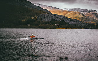 Kayaker paddling on a lake with snow-capped mountains