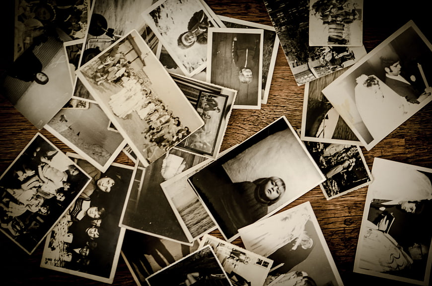 Scattered vintage black and white photographs on wooden table