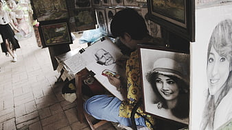 Street artist drawing charcoal portrait on sidewalk
