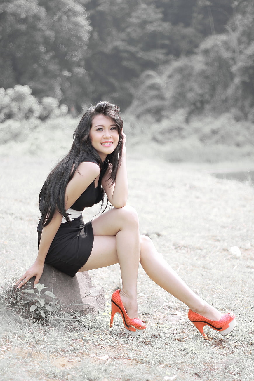 Woman in Black Dress and Orange Heels Sitting in Nature