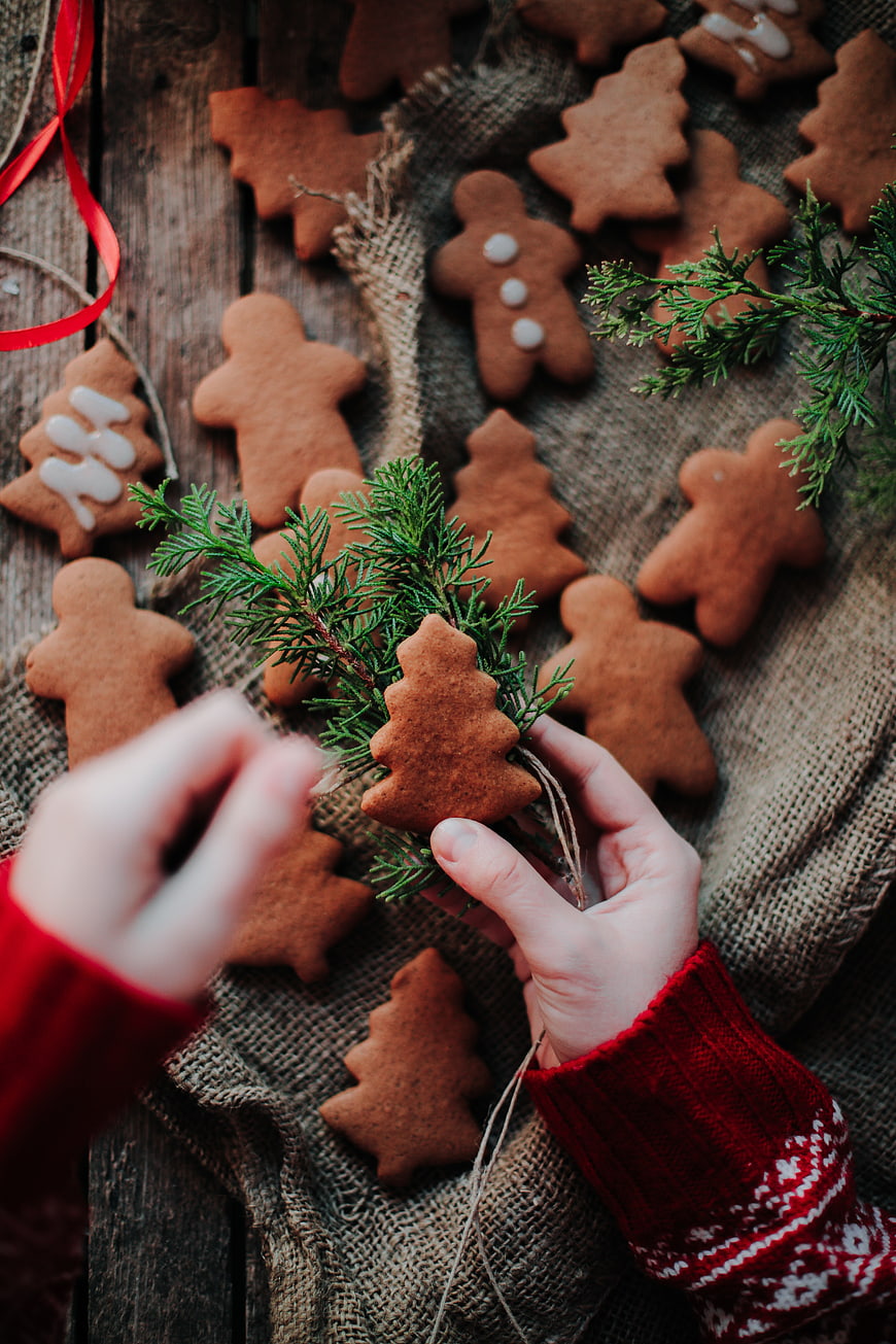 Hands holding gingerbread cookies on rustic wooden table