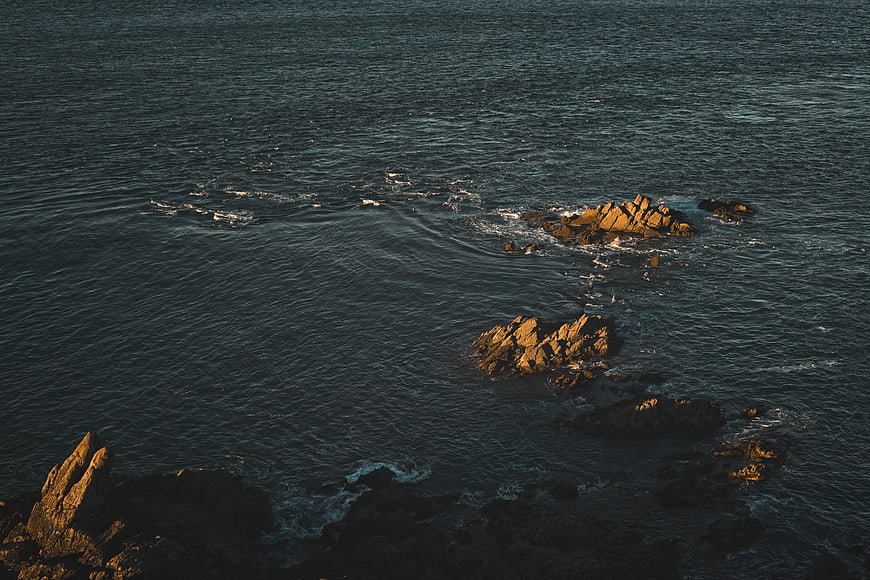 Aerial View of Rocky Outcrops in Dark Ocean Waters