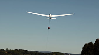 Glider Aircraft Towing Parachute Pilot Across Clear Blue Sky