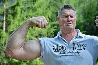 Senior Man Flexing Muscles Outdoors in Sailing Shirt